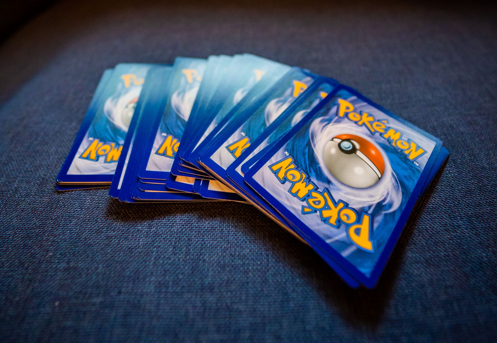 A fanned stack of Pokémon cards on a dark blue surface